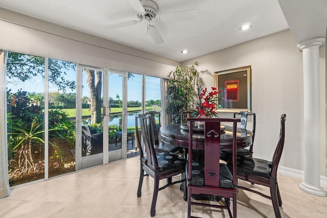 dining room with decorative columns, a water view, and ceiling fan