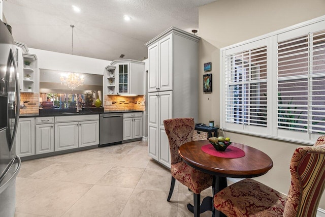 kitchen with sink, light tile patterned floors, appliances with stainless steel finishes, decorative backsplash, and a chandelier