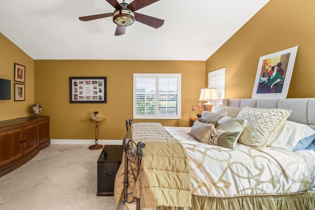 tiled bedroom featuring ceiling fan, vaulted ceiling, and a textured ceiling