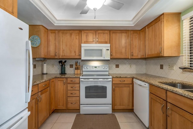 kitchen with a tray ceiling, light tile patterned floors, white appliances, and light stone countertops