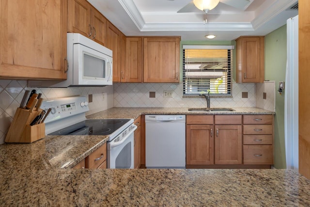 kitchen featuring sink, white appliances, tasteful backsplash, a tray ceiling, and light stone countertops