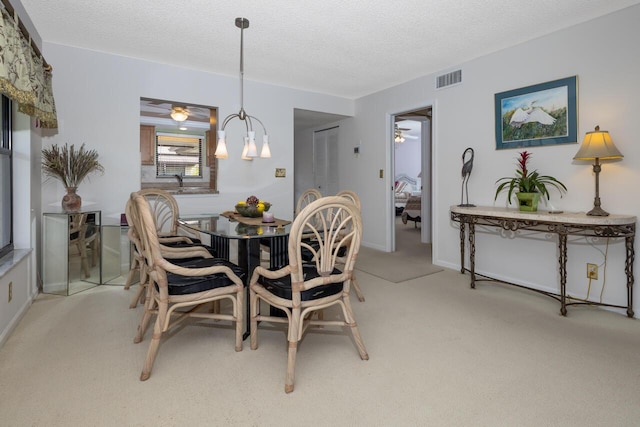 carpeted dining space with ceiling fan with notable chandelier and a textured ceiling