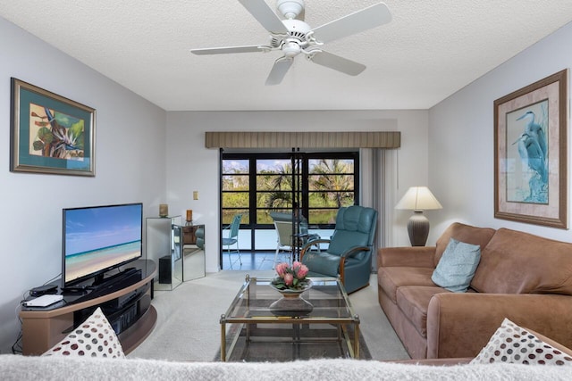 living room featuring ceiling fan, light carpet, and a textured ceiling