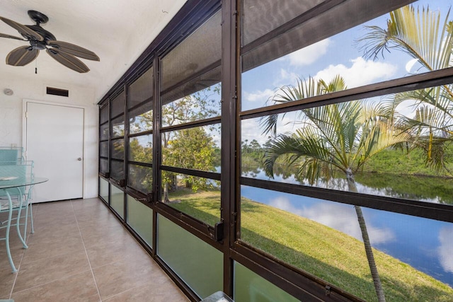 unfurnished sunroom featuring ceiling fan and a water view