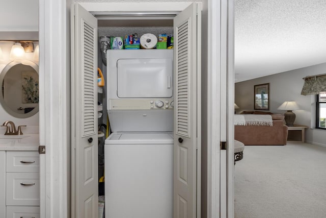 laundry room featuring stacked washer and dryer, sink, a textured ceiling, and carpet