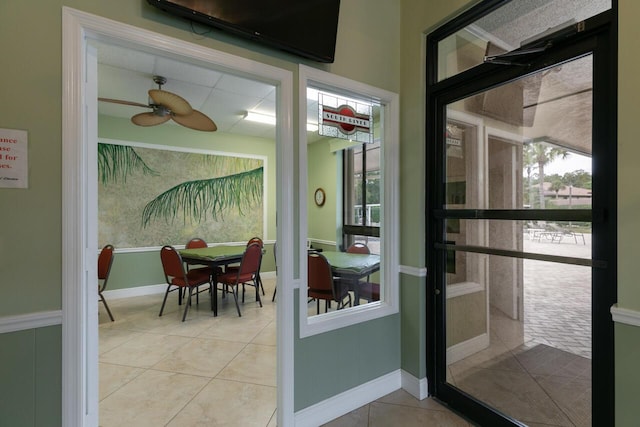 doorway with light tile patterned floors and ceiling fan