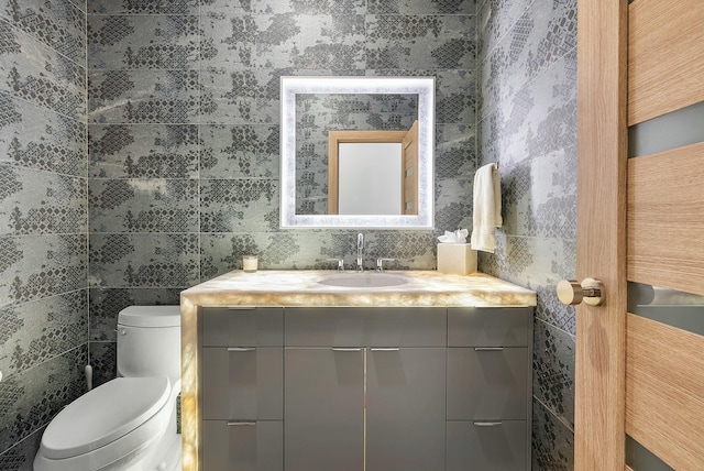 bathroom with vanity, tile walls, and toilet