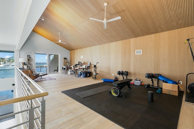 exercise area featuring ceiling fan, hardwood / wood-style floors, a towering ceiling, a water view, and wooden ceiling