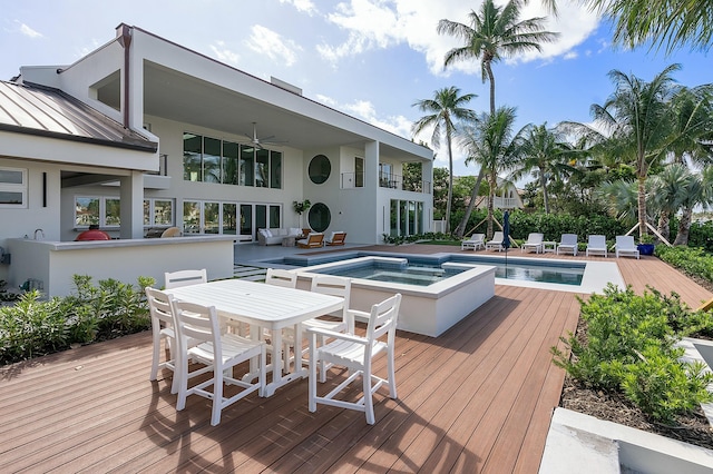 wooden terrace featuring ceiling fan and a pool with hot tub