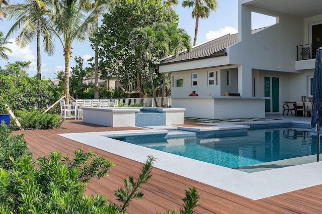 view of swimming pool featuring a wooden deck, exterior bar, and a jacuzzi