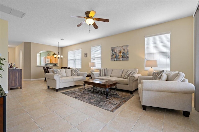 tiled living room featuring ceiling fan with notable chandelier, a wealth of natural light, and a textured ceiling