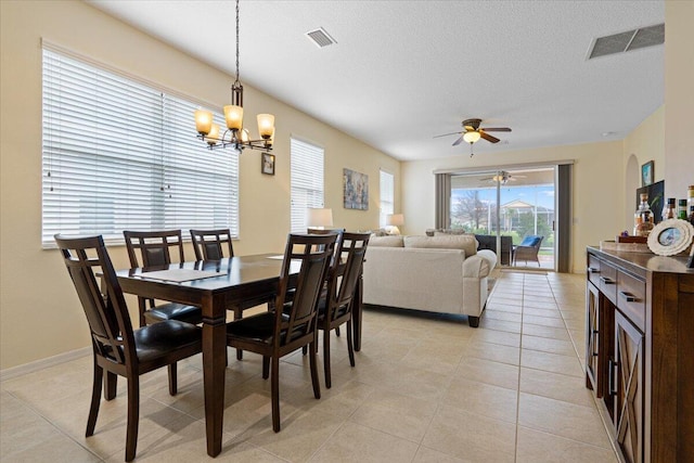 dining area featuring light tile patterned floors, ceiling fan with notable chandelier, and a textured ceiling