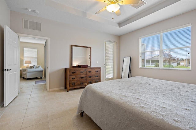 tiled bedroom with a raised ceiling and ceiling fan