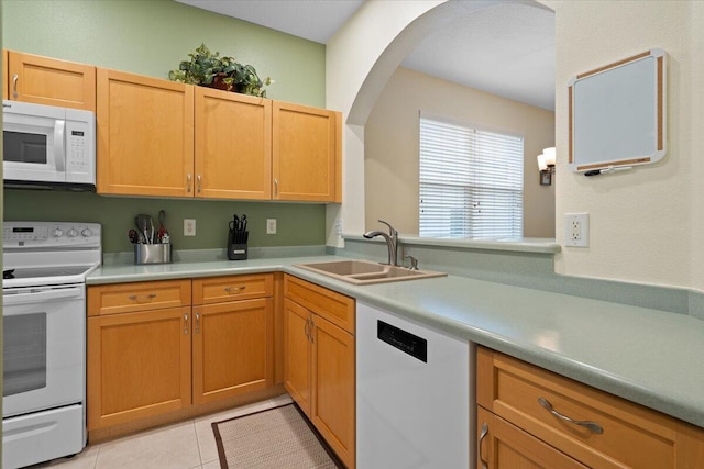 kitchen featuring sink, light tile patterned floors, and white appliances