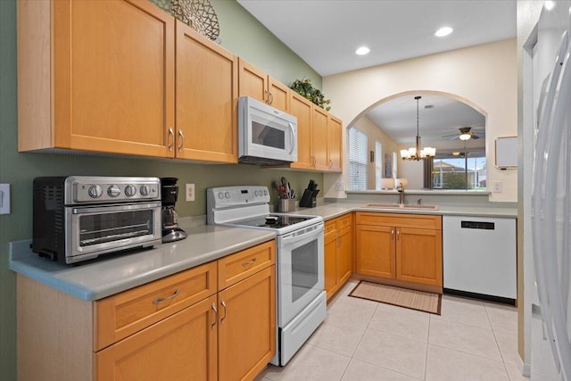 kitchen with light tile patterned flooring, sink, hanging light fixtures, a notable chandelier, and white appliances