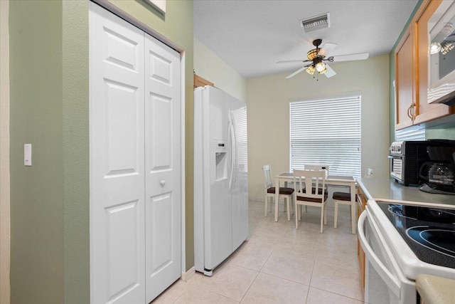 kitchen featuring light tile patterned flooring, a textured ceiling, ceiling fan, and white appliances