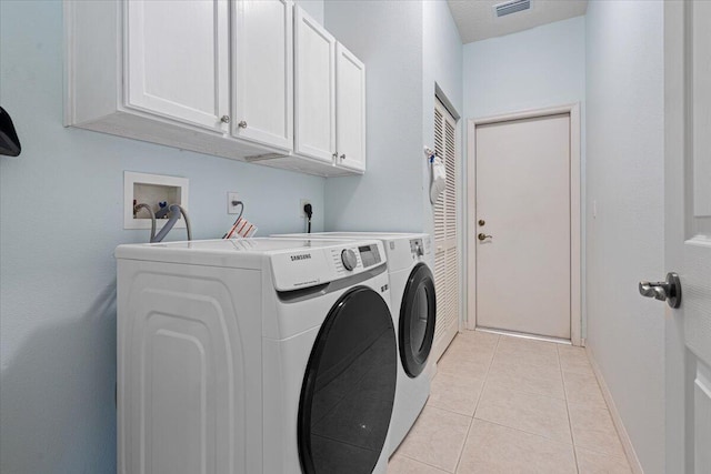 laundry room featuring cabinets, light tile patterned flooring, and washing machine and clothes dryer