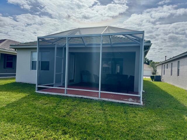 rear view of property with a lanai and a lawn