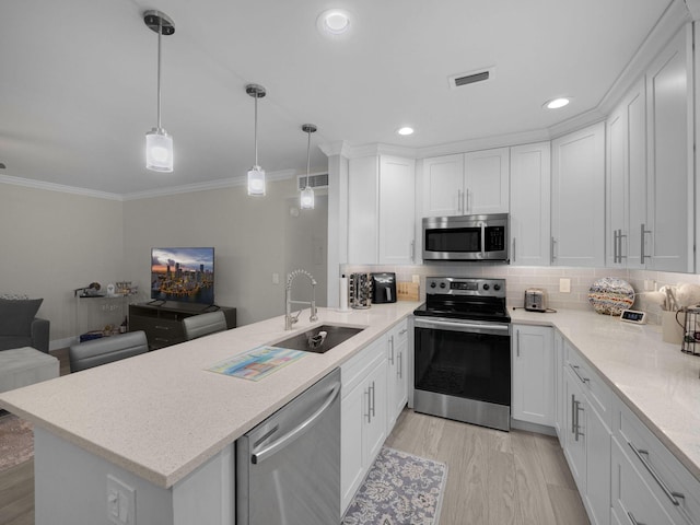 kitchen with sink, kitchen peninsula, pendant lighting, stainless steel appliances, and white cabinets