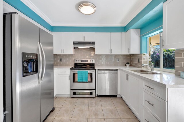 kitchen with appliances with stainless steel finishes, pendant lighting, white cabinets, backsplash, and light tile patterned floors