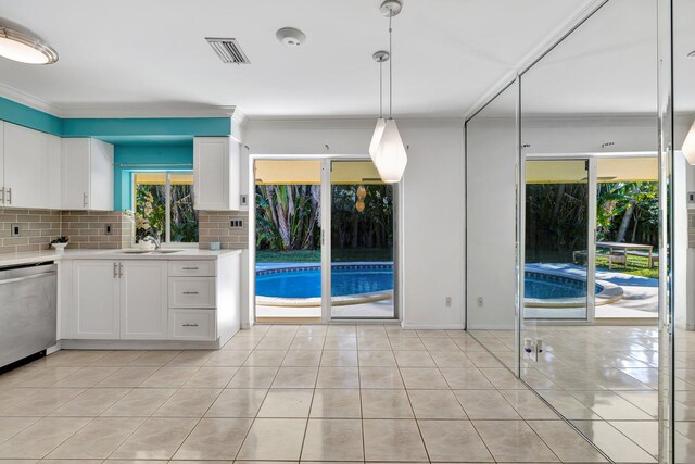 kitchen with crown molding, backsplash, hanging light fixtures, white cabinets, and stainless steel dishwasher