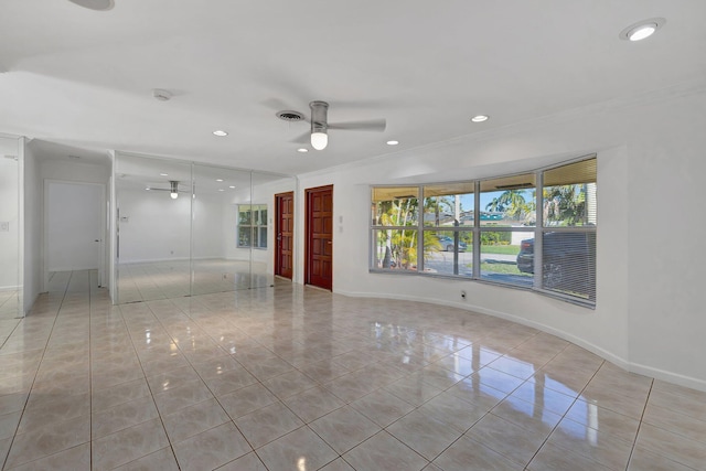 tiled empty room with ceiling fan and ornamental molding