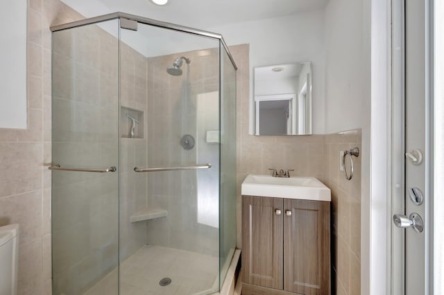 bathroom featuring tile walls, toilet, a shower stall, and vanity