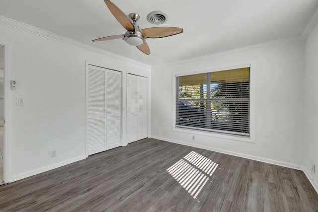 unfurnished bedroom with ornamental molding, visible vents, baseboards, and wood finished floors