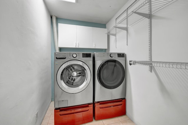 washroom with cabinet space, washing machine and clothes dryer, and light tile patterned floors