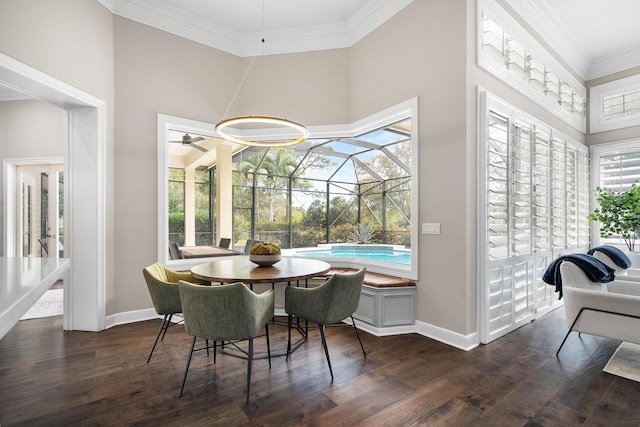 dining area with a high ceiling, ornamental molding, dark wood-type flooring, and ceiling fan