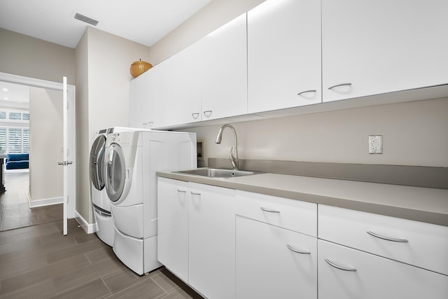 washroom with cabinets, sink, and washing machine and clothes dryer