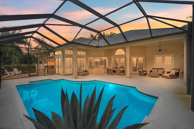 pool at dusk with ceiling fan, outdoor lounge area, a patio, and a lanai