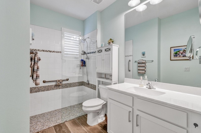 bathroom with a tile shower, vanity, and toilet