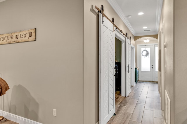 hall with ornamental molding and a barn door