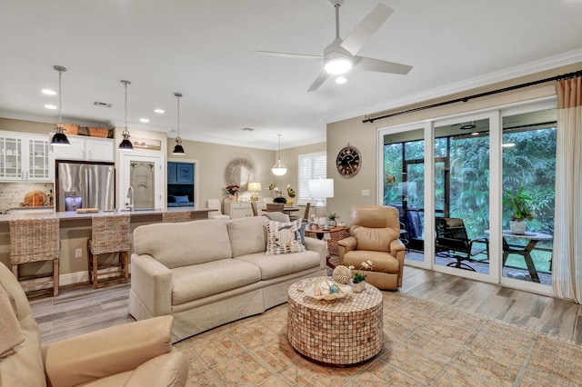 living room with sink, crown molding, light hardwood / wood-style flooring, and ceiling fan