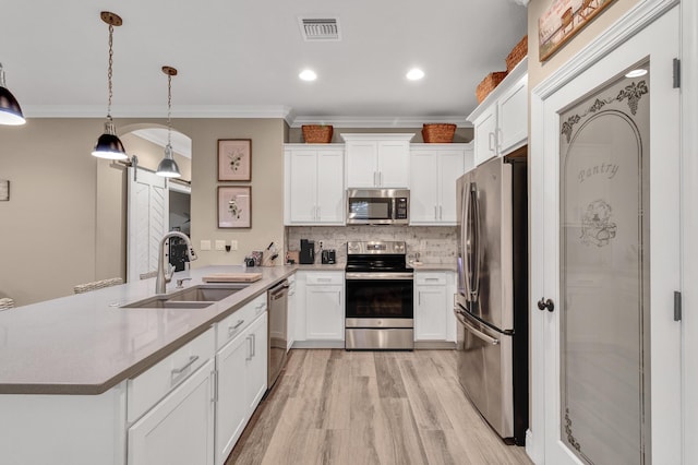 kitchen with appliances with stainless steel finishes, a barn door, hanging light fixtures, and white cabinets