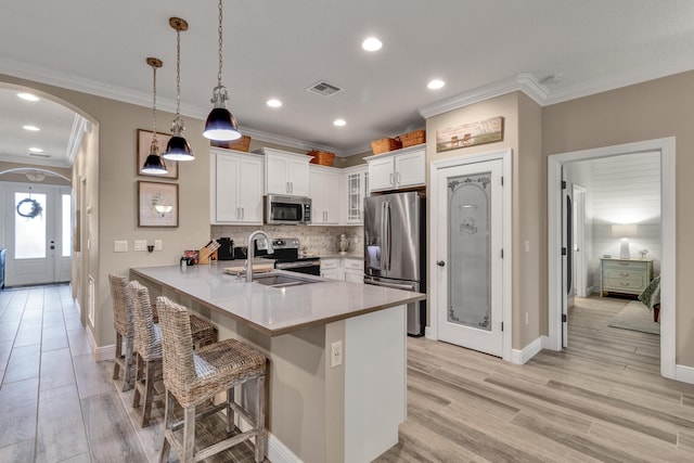 kitchen with appliances with stainless steel finishes, white cabinetry, sink, hanging light fixtures, and kitchen peninsula