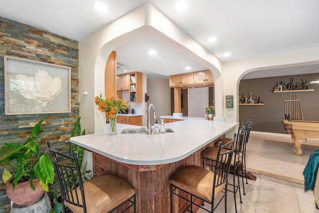 kitchen featuring sink, a kitchen breakfast bar, light tile patterned flooring, light brown cabinetry, and kitchen peninsula