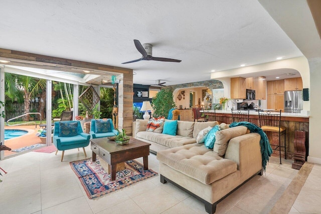 living room with light tile patterned flooring, ceiling fan, and sink