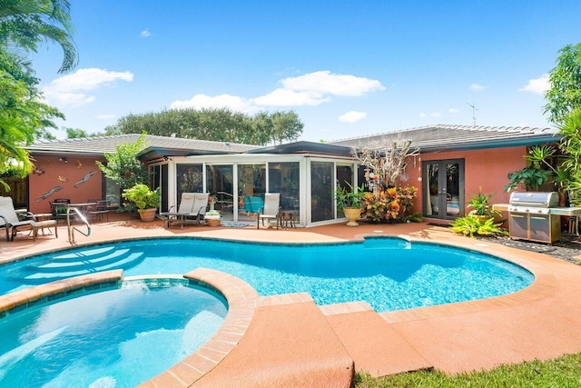 view of swimming pool featuring a patio, a sunroom, area for grilling, and french doors