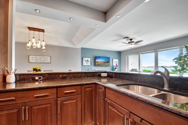 kitchen with ceiling fan, decorative light fixtures, sink, and dark stone countertops