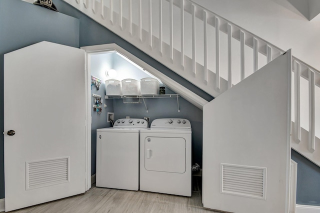 laundry area with separate washer and dryer and light hardwood / wood-style floors