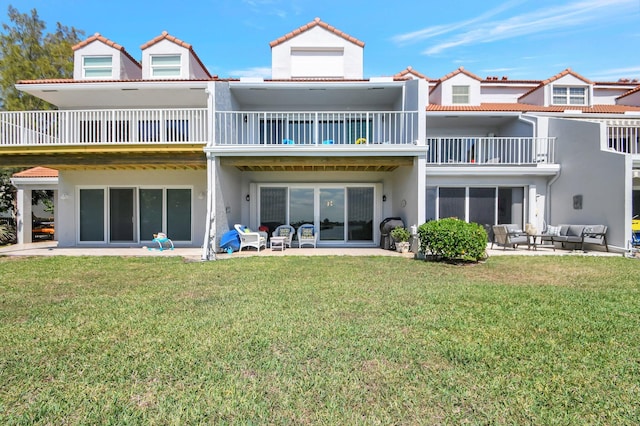 rear view of house with a balcony, an outdoor hangout area, a patio area, and a lawn