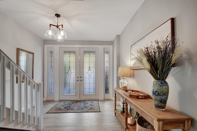 entrance foyer with french doors, a chandelier, and light hardwood / wood-style flooring