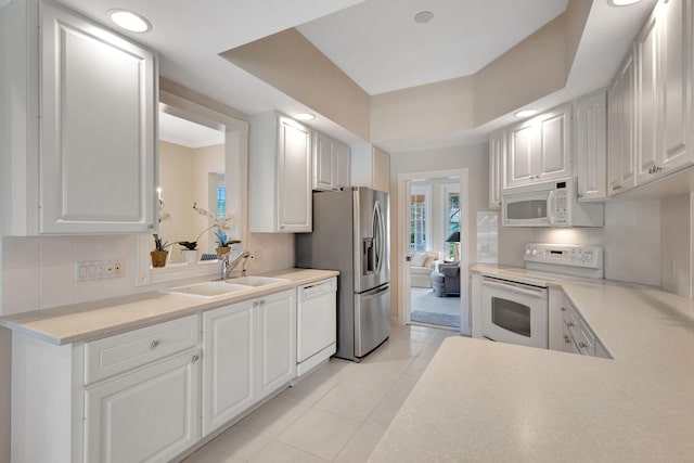 kitchen with white cabinetry, sink, light tile patterned floors, and white appliances