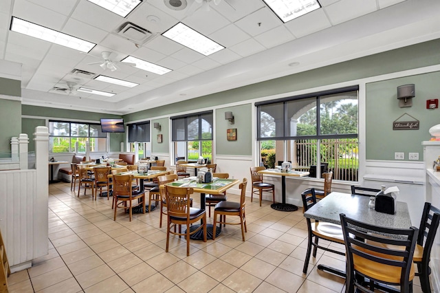 tiled dining room with a drop ceiling and ceiling fan