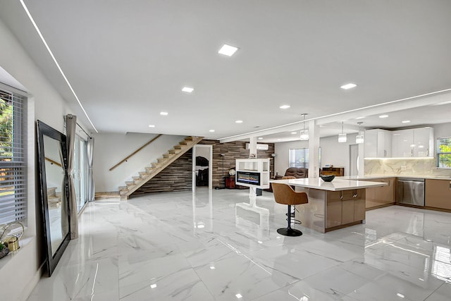 kitchen featuring a kitchen bar, a center island, stainless steel dishwasher, white cabinets, and backsplash