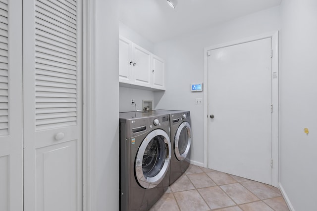 clothes washing area with cabinets, light tile patterned floors, and independent washer and dryer