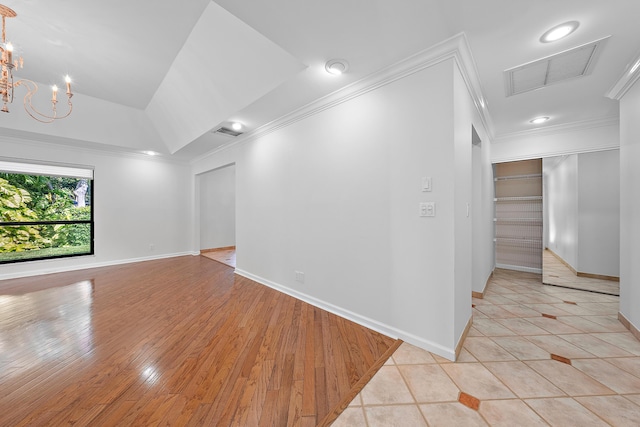 spare room with an inviting chandelier, light tile patterned floors, a tray ceiling, and ornamental molding