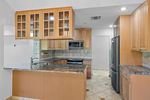 kitchen with sink, stainless steel appliances, kitchen peninsula, and dark stone counters